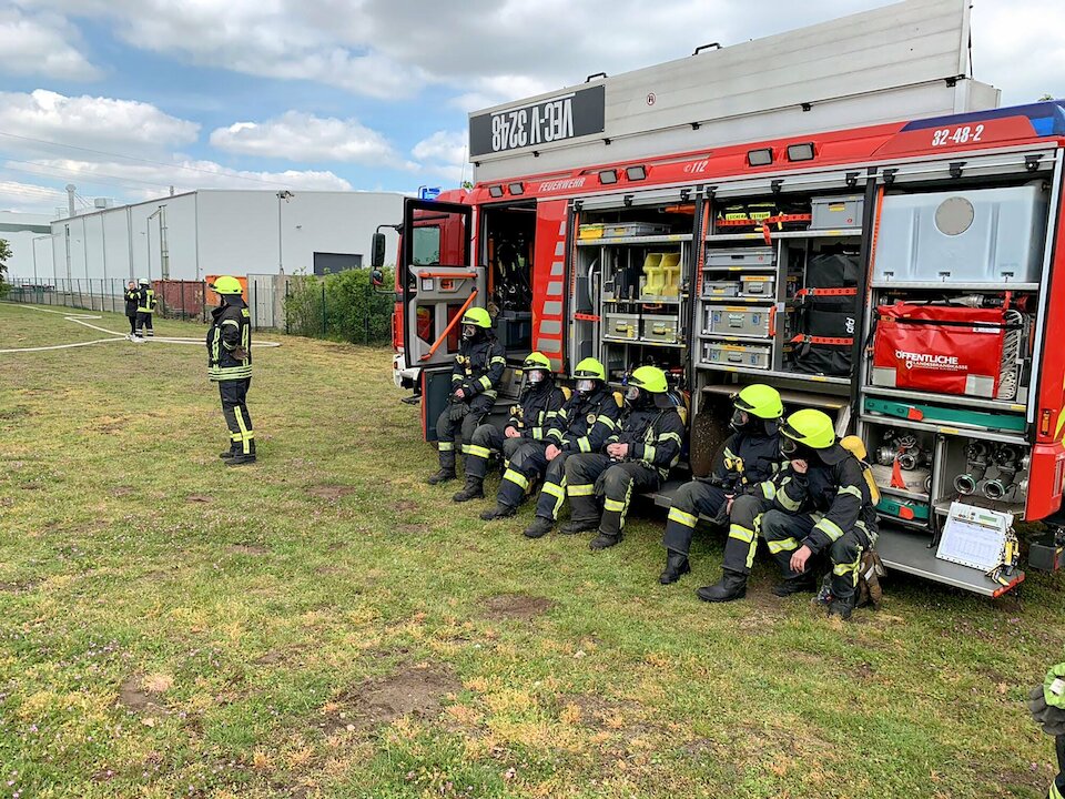 Kameraden und Kameradinnen neben einem Einsatzwagen